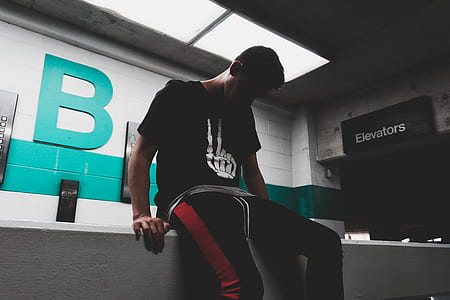 man wearing black sweatpants sitting on ledge thumbnail
