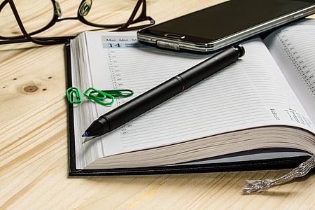 black click pen on top of notebook near with three paper clips thumbnail