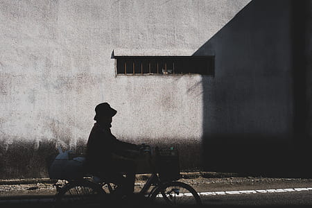 silhouette of man riding bike near gray wall thumbnail