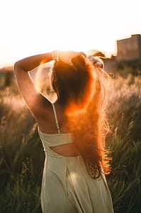 woman standing while holding her hair while standing near green grass field during daytime thumbnail