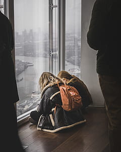 woman sitting on brown parquet floor while looking down thumbnail