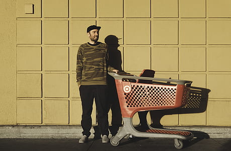 man in camouflage sweater holding red shopping cart thumbnail