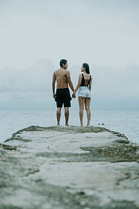 couple holding hands and standing on rock thumbnail