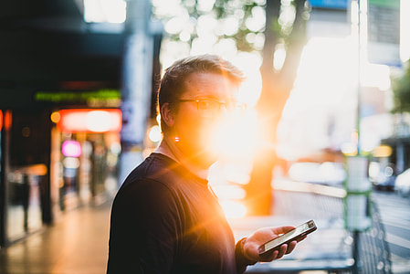 man standing beside tree while holding phone thumbnail