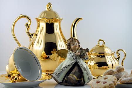 angel playing wind instrument figurine beside gold-colored teapots and teacup thumbnail
