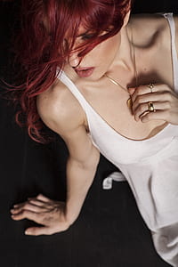 woman in white spaghetti strap top holding gold-colored necklace thumbnail