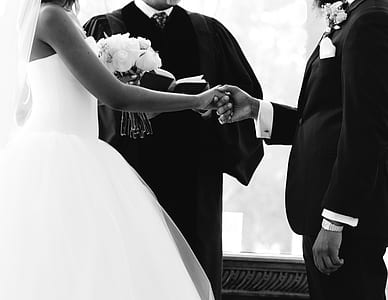 grayscale photo of couple standing in front of man holding bible thumbnail