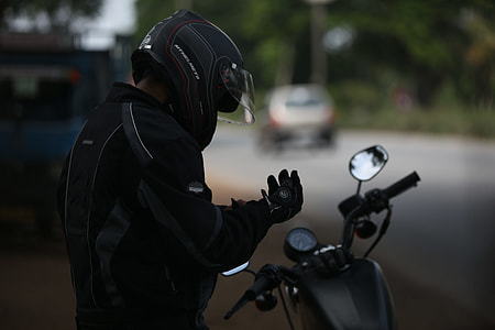 shallow focus photography of man in black jacket in front of motorcycle thumbnail