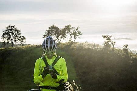 man holding smartphone standing beside bicycle thumbnail