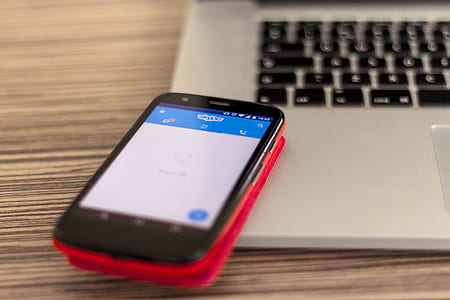 black and red Android smartphone on MacBook Pro on tabletop thumbnail