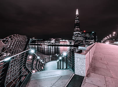 gray concrete stair with black concrete railing near body of water and gray concrete road at nighttime thumbnail