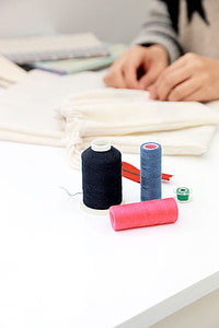 three assorted-color thread spools on white table thumbnail