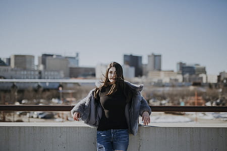woman leaning on building roof fence while looking at the camera thumbnail