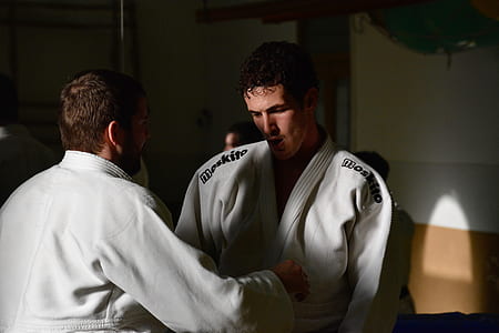 two men wearing karati gi standing near white wall thumbnail