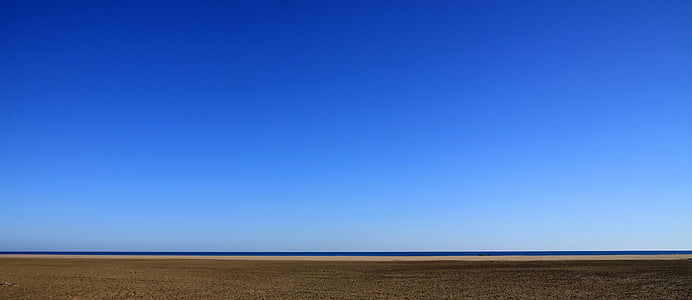 desert field with ocean during daytime thumbnail