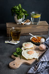 sunny side up eggs served with pepper on brown wooden chopping board thumbnail