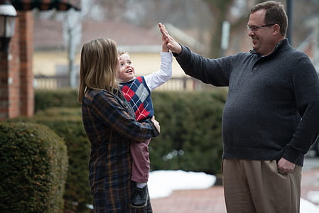 woman carrying boy hive five with man while smiling thumbnail