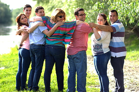group of people forming circle standing on grass field thumbnail