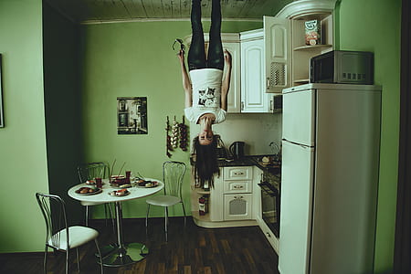 woman standing on ceiling beside white top-mount refrigerator in house thumbnail