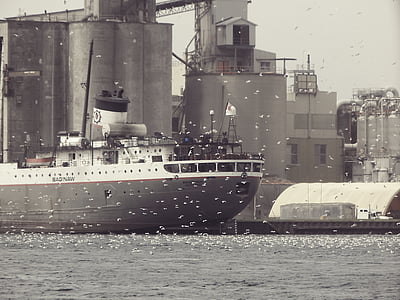 gray and white ship beside gray building at daytime thumbnail