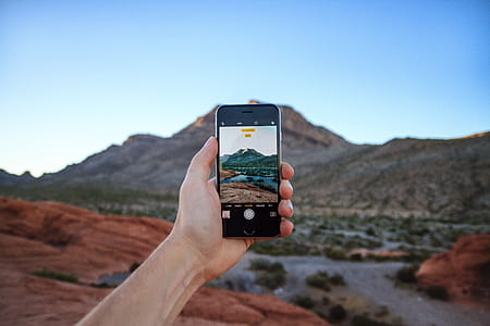 person holding space gray iPhone 6 taking photo of mountain thumbnail