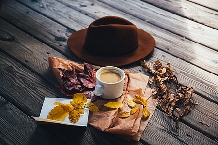 cup of coffee beside brown hat and yellow leaves thumbnail