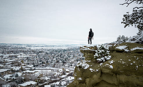 man standing on cliff near houses thumbnail