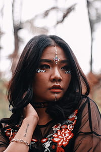 person wearing rhinestone face attachment holding her neck thumbnail
