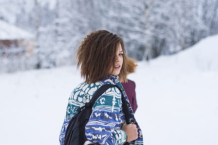 Selective Focus Portrait Photograph of Woman Wearing Blue, Green, and White Tribal Jacket and Black Backpack Outfit thumbnail