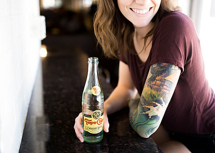 woman in brown scoop-neck top holding beverage bottle thumbnail
