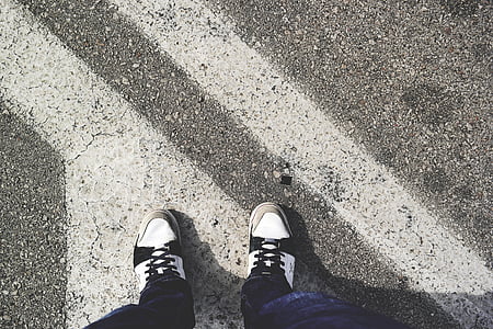 person wearing black-and-white sneaker standing on road at daytime thumbnail