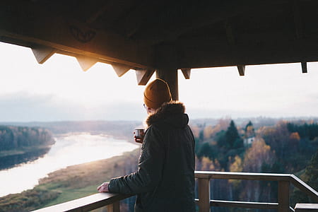 person standing on balcony holding cup of coffee thumbnail