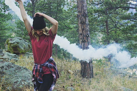 woman playing smoke in the woods during daytime thumbnail
