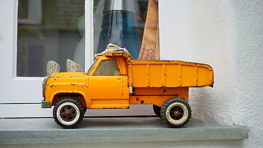 orange dump truck toy placed near glass panel window thumbnail