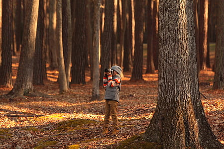 toddler standing near trees while taking picture during daytime thumbnail