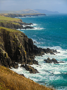 black rocky cliffs facing body of water thumbnail