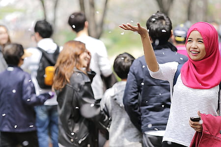Woman Wearing Red Hijab Behind Person Wearing Black Jacket thumbnail