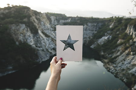 Person Holding Star Cutout Paper Facing Mountain thumbnail