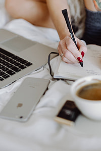 Woman working on a laptop while enjoying a breakfast coffee and chocolate in bed thumbnail