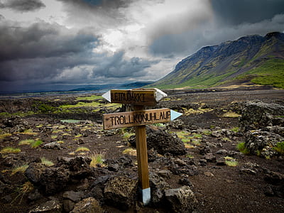 photography of brown wooden arrow signage on ground near mountains thumbnail