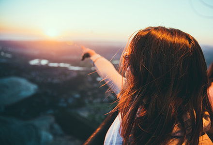 woman pointing to the sun during sun set thumbnail