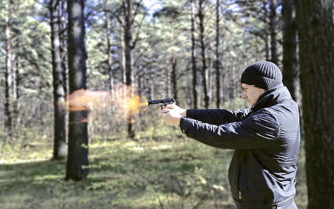 man firing semi-automatic rifle in a forest during daytime thumbnail