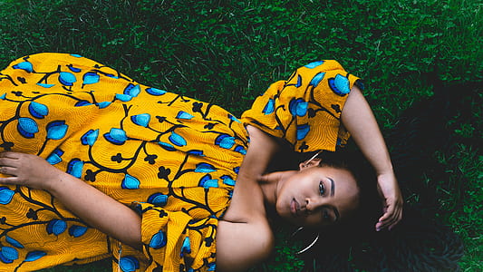 woman laying on green grass while holding her hair thumbnail