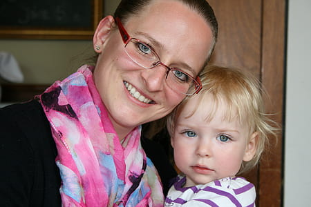 woman wearing eyeglasses carrying toddler in striped top thumbnail