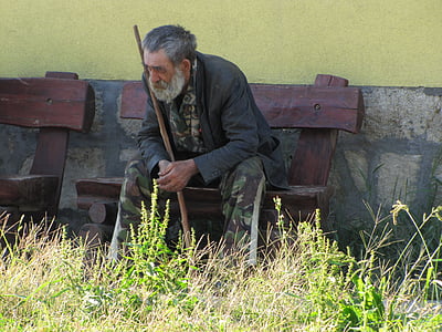 man sitting on bench holding cane at daytime thumbnail