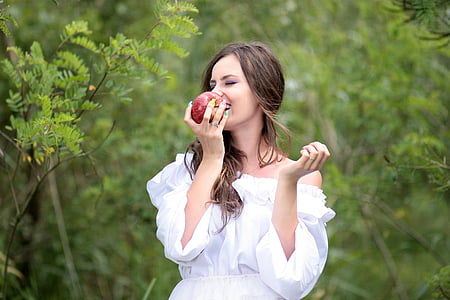 woman in white off-shoulder dress holding red apple thumbnail
