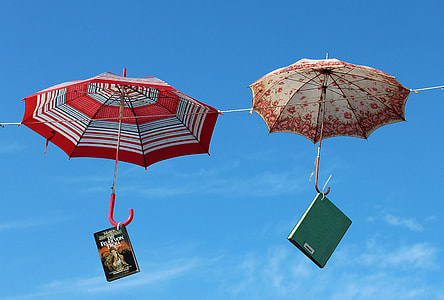 two red and brown umbrella hanging on wire with to books thumbnail