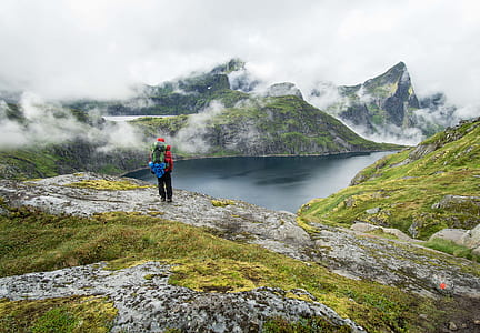 man standing on stone staring at body of water thumbnail