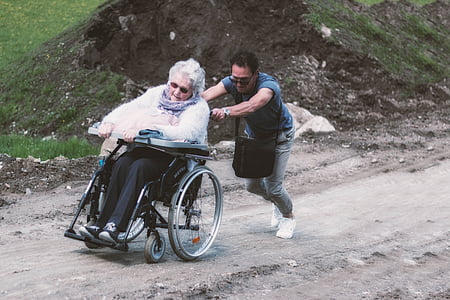 man pushing adult woman's wheelchair during daytime thumbnail