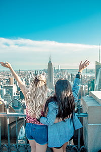 two women standing on building rooftop front of Empire State Building during daytime thumbnail